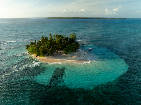 Aerial view of Guyam Island with its lush palm trees white sandy beach and turquoise waters surrounded by the deep blue sea in General Luna Caraga Philippines. Aerial view of Guyam Island with its lush palm trees white sandy beach and turquoise waters surrounded by the deep blue sea in General Luna Caraga Philippines.