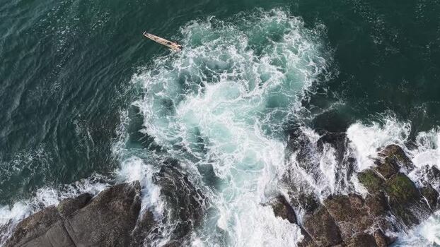 Aerial view of waves crashing on rocks with a small boat India. Aerial view of waves crashing on rocks with a small boat India.