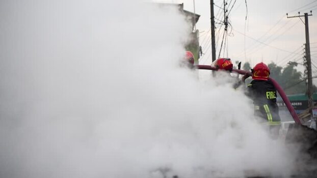 View of firefighters battling a fire with thick smoke Bangladesh. View of firefighters battling a fire with thick smoke Bangladesh.