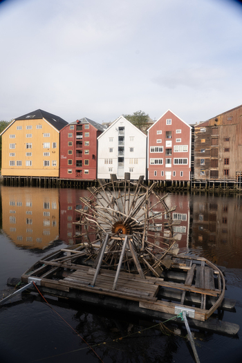 View of colorful wooden warehouses on the Nidelva river with a wooden water wheel in the foreground Trondheim Trondelag Norway. View of colorful wooden warehouses on the Nidelva river with a wooden water wheel in the foreground Trondheim Trondelag Norway.