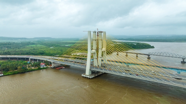 Aerial view of the modern cable stayed Zuari Bridge spanning the river with lush green banks under a cloudy sky in Cortalim Goa India.