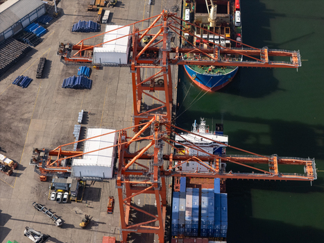 Aerial view of industrial port cranes loading cargo containers onto a large ship at the port in Bajos de Haina San Cristobal Province Dominican Republic.