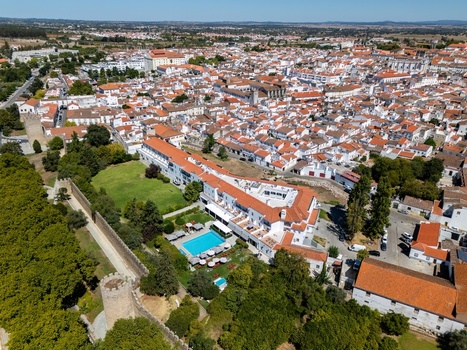 Aerial view of the historic city of Evora featuring white buildings with terracotta rooftops a hotel with a pool and ancient stone fortifications in Evora Evora District Portugal. Aerial view of the historic city of Evora featuring white buildings with terracotta rooftops a hotel with a pool and ancient stone fortifications in Evora Evora District Portugal.