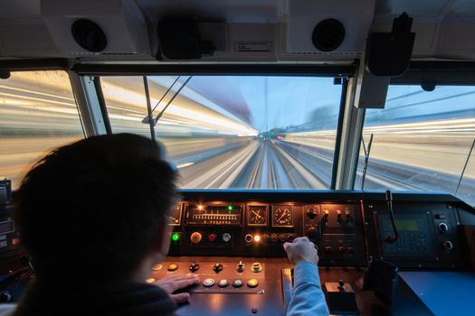 View of a train driver operating the controls in the cab of a high speed train with motion blur on the tracks at Amsterdam Airport Schiphol Schiphol Noord Holland Netherlands. View of a train driver operating the controls in the cab of a high speed train with motion blur on the tracks at Amsterdam Airport Schiphol Schiphol Noord Holland Netherlands.