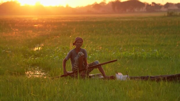 View of a fisherman in a boat at sunset in Bogura Bangladesh. View of a fisherman in a boat at sunset in Bogura Bangladesh.