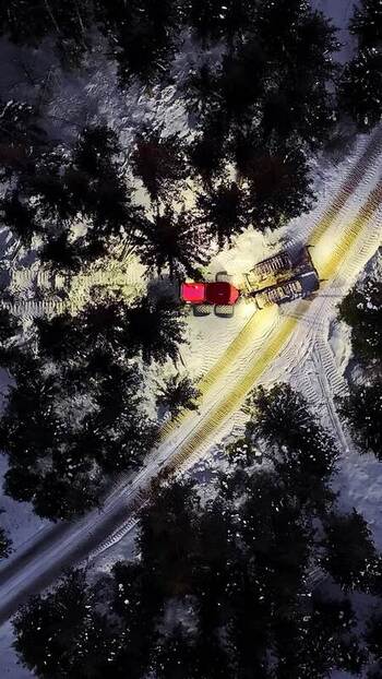 Aerial view of snow groomer in snowy forest Latvia.