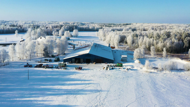 Aerial view of a farm building surrounded by snow covered fields and frost covered trees in Latvija. Aerial view of a farm building surrounded by snow covered fields and frost covered trees in Latvija.