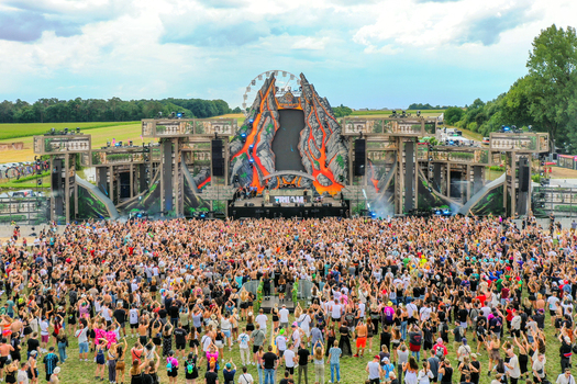 Herzogenaurach Germany 24 July 2025 Aerial view of the Open Beatz Festival featuring a large crowd gathered before a volcano themed main stage under a cloudy sky.