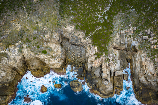 Aerial view of Jimmy Newells Harbour showing rugged granite cliffs crashing blue ocean waves and coastal vegetation in Albany WA Australia. Aerial view of Jimmy Newells Harbour showing rugged granite cliffs crashing blue ocean waves and coastal vegetation in Albany WA Australia.