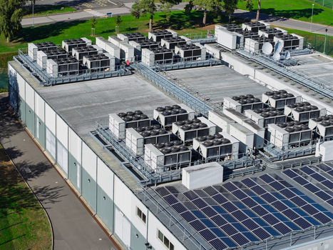 Aerial view of a data center roof featuring numerous HVAC cooling units and rows of solar panels in the United Kingdom.
