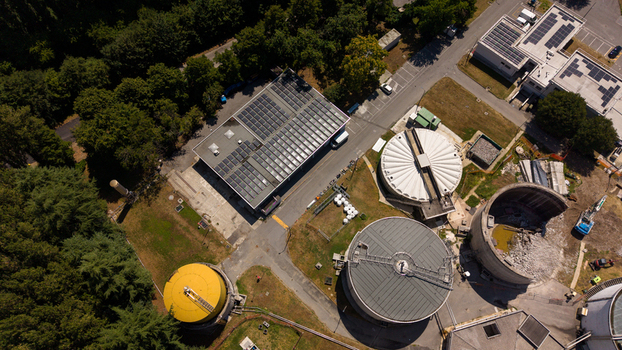 Aerial view of a wastewater treatment plant featuring circular tanks a building with solar panels and surrounding greenery in Milan Lombardy Italy. Aerial view of a wastewater treatment plant featuring circular tanks a building with solar panels and surrounding greenery in Milan Lombardy Italy.