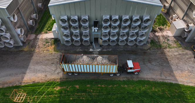 Aerial view of a poultry farm with ventilation fans a truck with a trailer of organic material and workers in protective suits in East Donegal Township Pennsylvania United States.