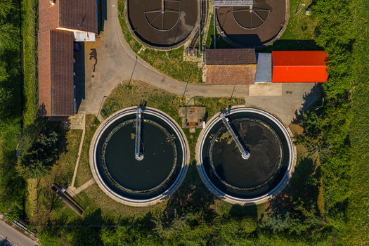 Aerial view of a wastewater treatment plant featuring circular sedimentation tanks and industrial buildings surrounded by green grass Kyjov South Moravian Region Czechia.