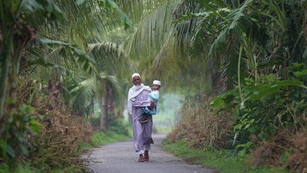 View of a man carrying a child on a path in Bogura Bangladesh. View of a man carrying a child on a path in Bogura Bangladesh.