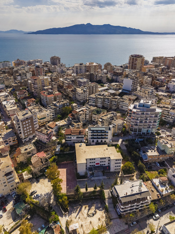 Aerial view of the coastal city of Saranda featuring dense urban architecture apartment buildings and the Ionian Sea in the background in Saranda Vlore County Albania. Aerial view of the coastal city of Saranda featuring dense urban architecture apartment buildings and the Ionian Sea in the background in Saranda Vlore County Albania.