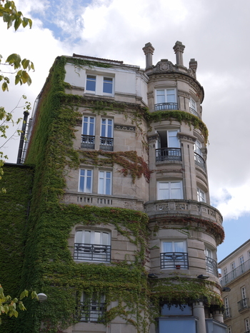 View of a historic stone building with ivy covered walls and a rounded corner section featuring balconies in Ourense Province of Ourense Spain.