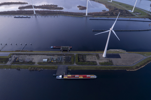Aerial view of Krammer locks featuring a large wind turbine a cargo ship carrying containers on the water and surrounding landscape in Bruinisse Zeeland Netherlands. Aerial view of Krammer locks featuring a large wind turbine a cargo ship carrying containers on the water and surrounding landscape in Bruinisse Zeeland Netherlands.