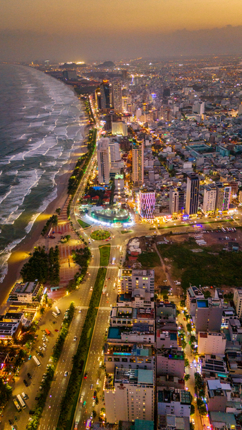 Aerial view of the coastal city of Da Nang at night featuring illuminated high rise buildings a vibrant beachfront and glowing city streets Da Nang Vietnam. Aerial view of the coastal city of Da Nang at night featuring illuminated high rise buildings a vibrant beachfront and glowing city streets Da Nang Vietnam.