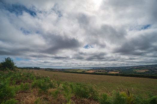 View of the Fowey River landscape with rolling fields lush greenery and a cloudy sky overlooking the town of Fowey Cornwall United Kingdom. View of the Fowey River landscape with rolling fields lush greenery and a cloudy sky overlooking the town of Fowey Cornwall United Kingdom.