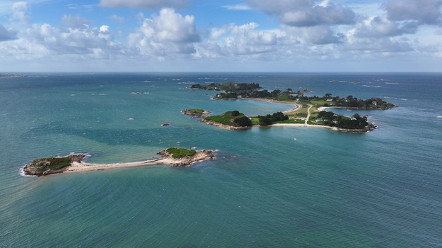 Aerial view of the lush green islands and turquoise waters of the Bay of Morlaix featuring sandy beaches and rocky outcrops under a cloudy sky in Carantec Brittany France. Aerial view of the lush green islands and turquoise waters of the Bay of Morlaix featuring sandy beaches and rocky outcrops under a cloudy sky in Carantec Brittany France.