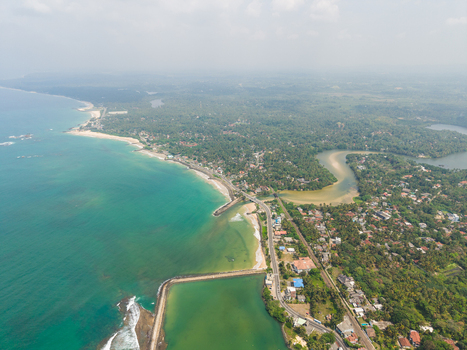 Aerial view of the tropical coastline with turquoise ocean waves sandy beaches and lush green vegetation along the shore in Hikkaduwa Southern Province Sri Lanka. Aerial view of the tropical coastline with turquoise ocean waves sandy beaches and lush green vegetation along the shore in Hikkaduwa Southern Province Sri Lanka.