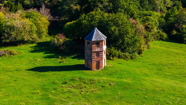 Aerial view of the historic brick folly at Pepperbox Hill surrounded by lush green fields and trees in Salisbury England United Kingdom. Aerial view of the historic brick folly at Pepperbox Hill surrounded by lush green fields and trees in Salisbury England United Kingdom.