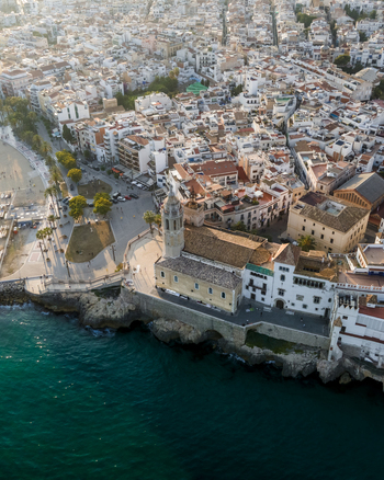 Aerial view of the Church of San Bartolome and Santa Tecla overlooking the Mediterranean Sea and the white walled old town in Sitges Catalonia Spain. Aerial view of the Church of San Bartolome and Santa Tecla overlooking the Mediterranean Sea and the white walled old town in Sitges Catalonia Spain.