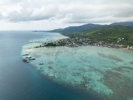 Aerial view of the shimmering turquoise waters meeting the lush green coastline revealing the town s sprawl Karimunjawa Central Java Indonesia. Aerial view of the shimmering turquoise waters meeting the lush green coastline revealing the town s sprawl Karimunjawa Central Java Indonesia.