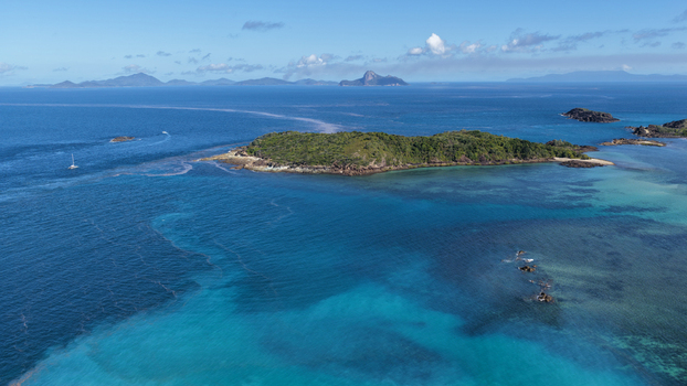 Aerial view of Chance Bay in the Whitsundays featuring vibrant turquoise waters coral reefs and lush tropical vegetation under a clear blue sky. Whitsundays Queensland Australia. Aerial view of Chance Bay in the Whitsundays featuring vibrant turquoise waters coral reefs and lush tropical vegetation under a clear blue sky. Whitsundays Queensland Australia.