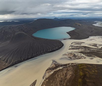 Aerial view of Landmannalaugar volcanic crater lake with turquoise water surrounded by dark volcanic slopes and a braided river system in Rangarthing ytra Iceland. Aerial view of Landmannalaugar volcanic crater lake with turquoise water surrounded by dark volcanic slopes and a braided river system in Rangarthing ytra Iceland.