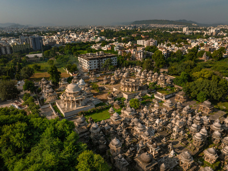 Aerial view of the historic Ahar Cenotaphs featuring numerous stone domes and intricate architecture surrounded by lush greenery in Udaipur Rajasthan India.