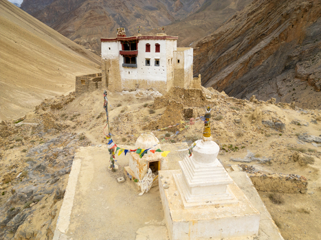 Aerial view of the historic Zanskar monastery featuring traditional white architecture and prayer flags set against the rugged mountain landscape of Zanskar Ladakh India.