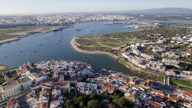 Aerial view of the coastal town of Ferragudo with its white washed houses historic church and boats anchored in the Arade River estuary in Ferragudo Faro District Portugal.