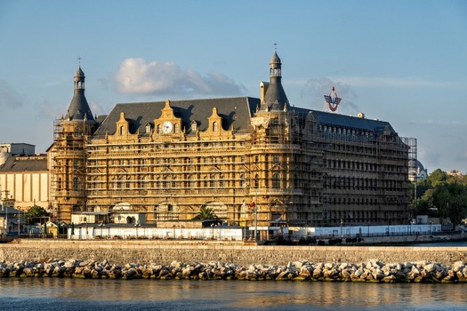 View of Haydarpasa Railway Station in Istanbul Turkey featuring historic architecture covered in scaffolding along the Bosphorus waterfront under a clear blue sky. View of Haydarpasa Railway Station in Istanbul Turkey featuring historic architecture covered in scaffolding along the Bosphorus waterfront under a clear blue sky.