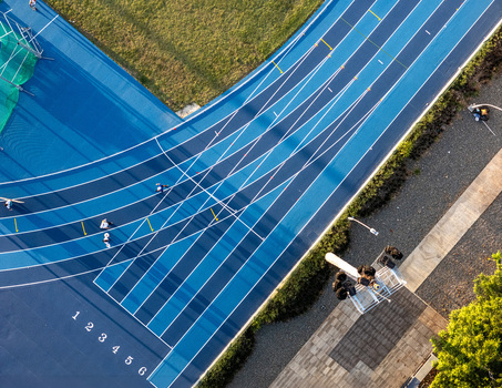 Aerial view of a blue running track with athletes training lane markings and surrounding greenery in Santo Domingo Distrito Nacional Dominican Republic.
