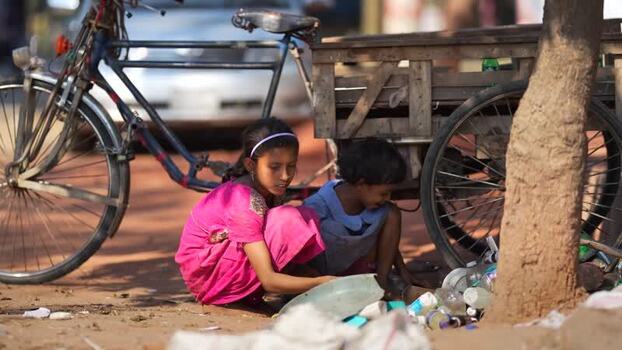 View of two girls sorting plastic bottles near a cart in Bangladesh. View of two girls sorting plastic bottles near a cart in Bangladesh.