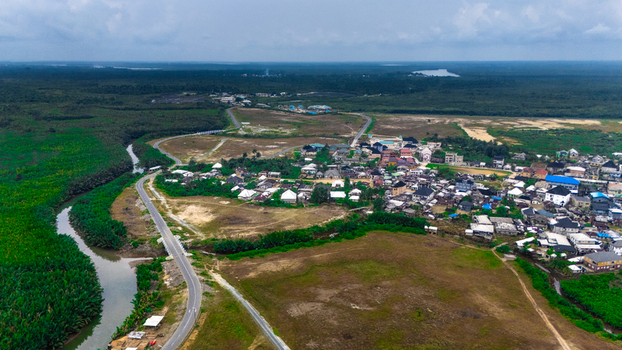 Aerial view of a rural settlement surrounded by lush mangrove forests winding rivers and open fields in Minima Rivers Nigeria.