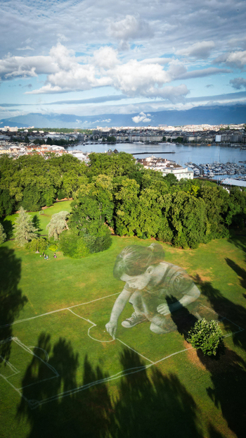 Aerial view of green park contrasting with the blue waters of Lake Geneva and the cityscape beyond Gen&egrave;ve Gen&egrave;ve Switzerland.