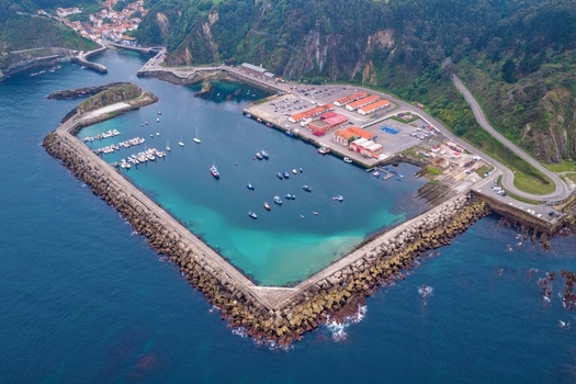 Aerial view of the port of Cudillero with its stone breakwater turquoise water and fishing boats moored near the green cliffs in Cudillero Asturias Spain. Aerial view of the port of Cudillero with its stone breakwater turquoise water and fishing boats moored near the green cliffs in Cudillero Asturias Spain.