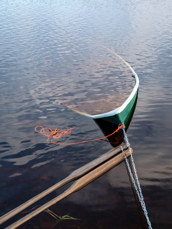 View of a partially submerged rowboat tied with a chain and rope to a wooden dock in a river after a flood in Muhos North Ostrobothnia Finland.