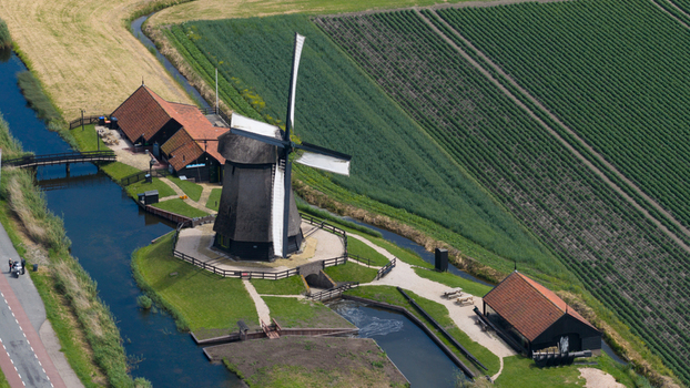 Aerial view of the historic Schermerhorn windmill surrounded by lush green fields and a canal in Schermerhorn North Holland Netherlands. Aerial view of the historic Schermerhorn windmill surrounded by lush green fields and a canal in Schermerhorn North Holland Netherlands.