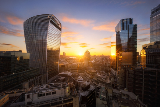 Aerial view of the London skyline at sunset featuring the curved facade of 20 Fenchurch Street and surrounding glass skyscrapers reflecting the golden light in London England United Kingdom. Aerial view of the London skyline at sunset featuring the curved facade of 20 Fenchurch Street and surrounding glass skyscrapers reflecting the golden light in London England United Kingdom.