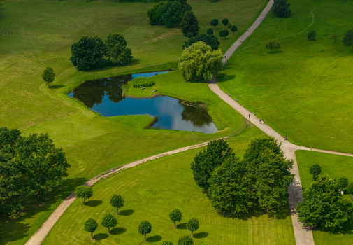 Aerial view of a park featuring a small pond winding walking paths lush green lawns and scattered trees in Kaunas Kaunas County Lithuania.