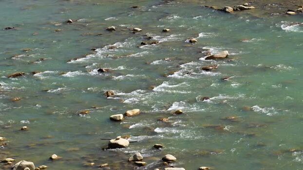 View of a turquoise river flowing over smooth rocks Nepal.