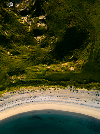 Aerial view of the curved sandy beach and lush green hills of Tangstad with clear blue water and rocky outcrops Leknes Nordland Norway. Aerial view of the curved sandy beach and lush green hills of Tangstad with clear blue water and rocky outcrops Leknes Nordland Norway.