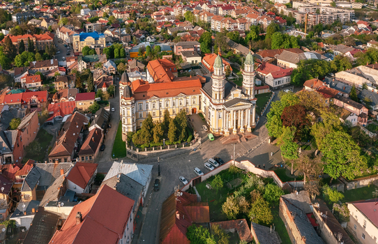 Aerial view of the golden hued Uzhhorod Cathedral rises majestically amidst a tapestry of terracotta roofs and verdant trees Uzhhorod Zakarpattia Oblast Ukraine. Aerial view of the golden hued Uzhhorod Cathedral rises majestically amidst a tapestry of terracotta roofs and verdant trees Uzhhorod Zakarpattia Oblast Ukraine.