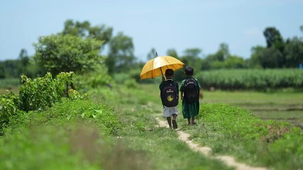 View of two students walking with a yellow umbrella Bangladesh.