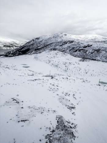 Aerial view of snowy mountain slopes frozen ponds and sparse trees under an overcast sky Ersfjord Troms Norway. Aerial view of snowy mountain slopes frozen ponds and sparse trees under an overcast sky Ersfjord Troms Norway.