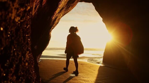 View of a person exiting a sea cave onto a beach New Zealand. View of a person exiting a sea cave onto a beach New Zealand.