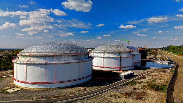 Aerial view of oil storage tanks with white domes and red piping in an industrial facility under a blue sky with clouds in Kovin Vojvodina Serbia. Aerial view of oil storage tanks with white domes and red piping in an industrial facility under a blue sky with clouds in Kovin Vojvodina Serbia.